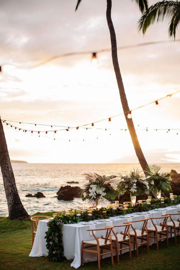 Oceanfront reception table at sunset under palm trees