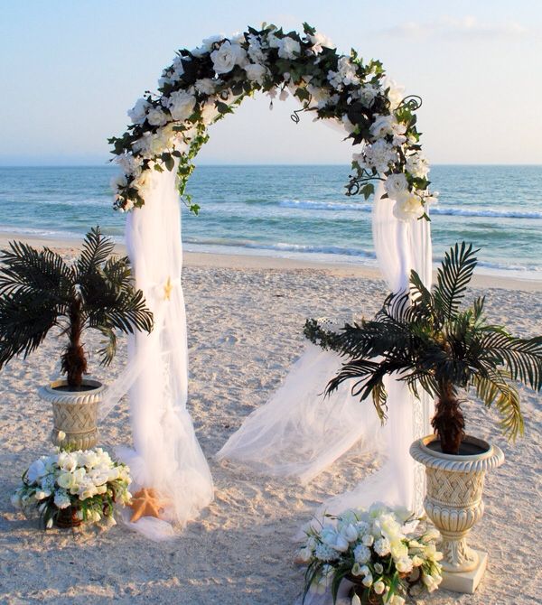 White floral arch ceremony setup on the beach