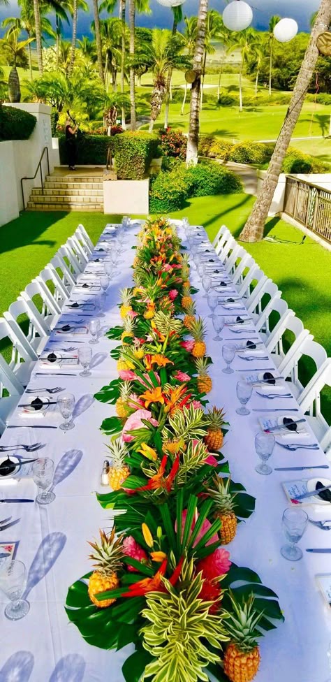 Long reception table with tropical garland on a lawn
